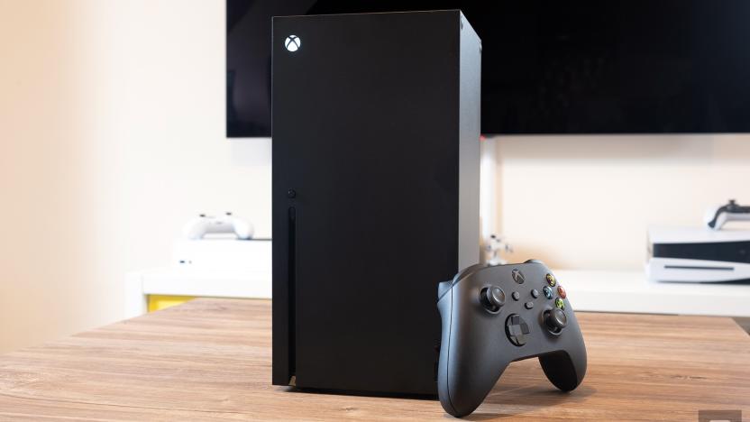 An Xbox Series X stood vertically on a wooden table, with a controller propped up against it.