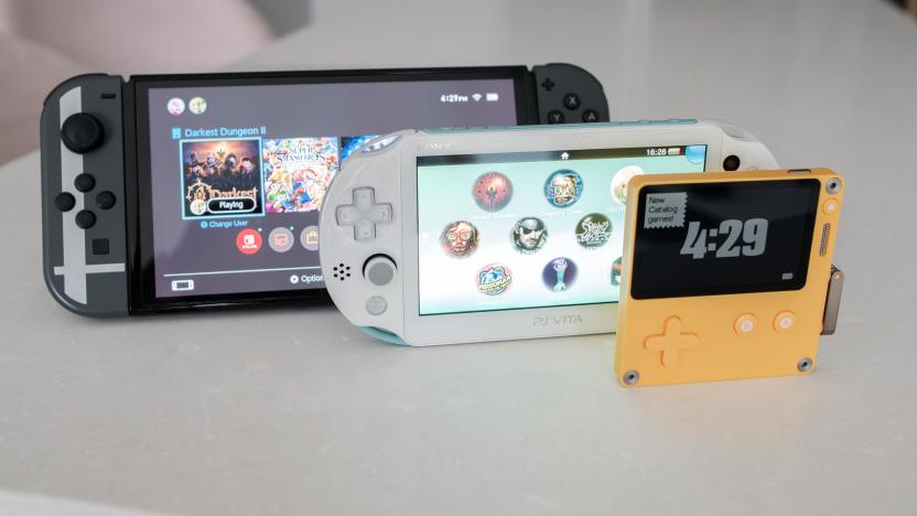 A Switch OLED sits next to a PS Vita and Panic Playdate. 
