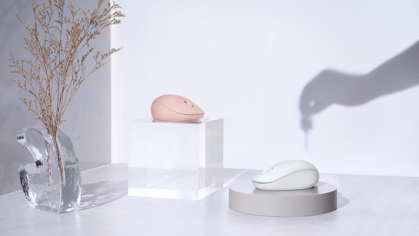 A pink and white mouse on a table with the shadow of a hand holding a dropper in the background.