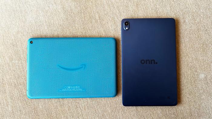 The teal blue Amazon Fire HD 8 and navy blue Walmart Onn 8" tablets rest face down on a light brown couch cushion.