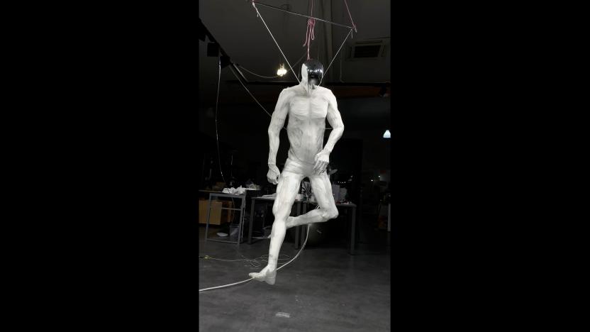 A white, muscle-y robot kicking its legs on a hook.