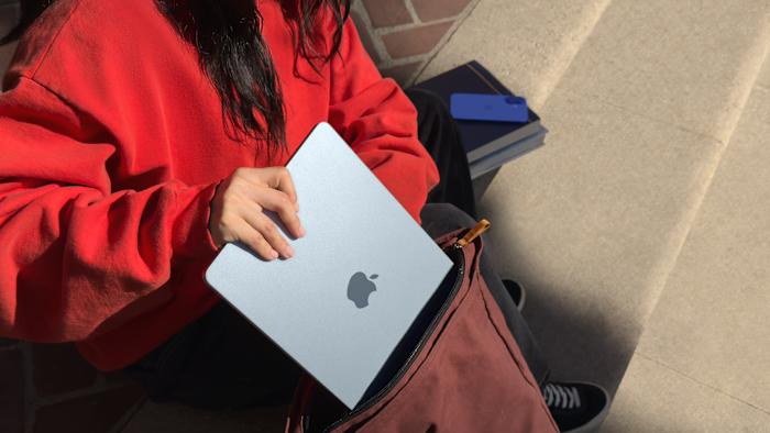 Lifestyle marketing photo of a person sliding the MacBook Air into a backpack.