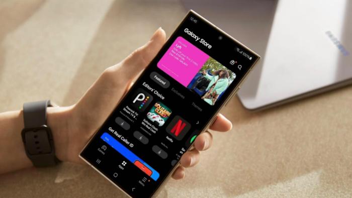 A hand holding a phone with its open showing the Samsung Galaxy Store.
