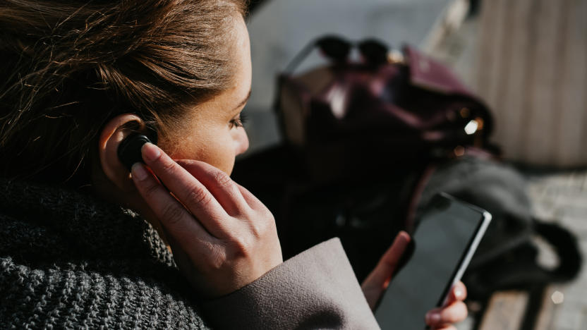 person with mobile phone and bluetooth headset, typing on telephone in the street