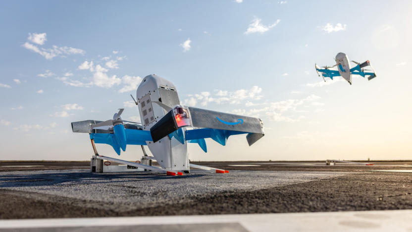 One white and blue drone on the ground and one in the sky.