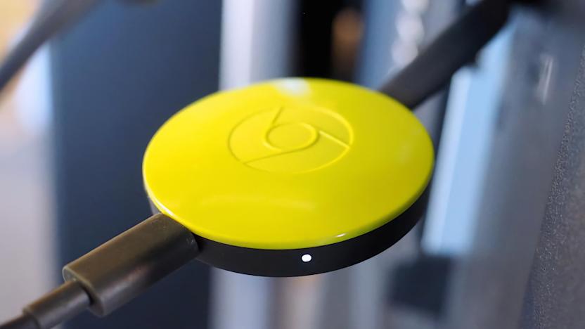 A yellow second-generation Chromecast plugged in to a TV.