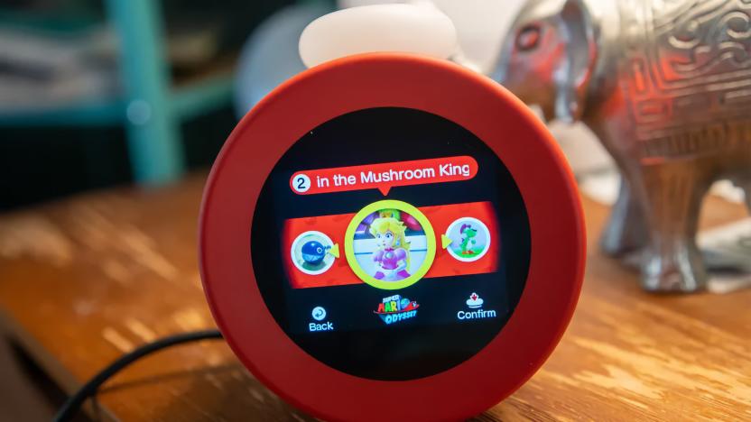 A red circular Alarmo alarm clock sitting on a bedside table.